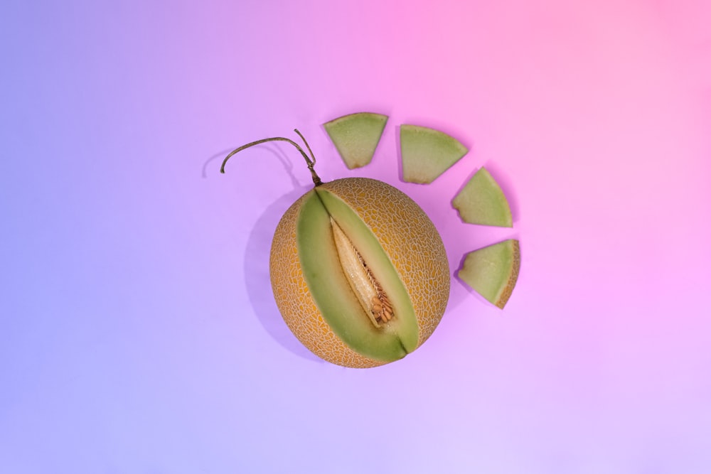 a cut in half kiwi fruit on a purple and pink background