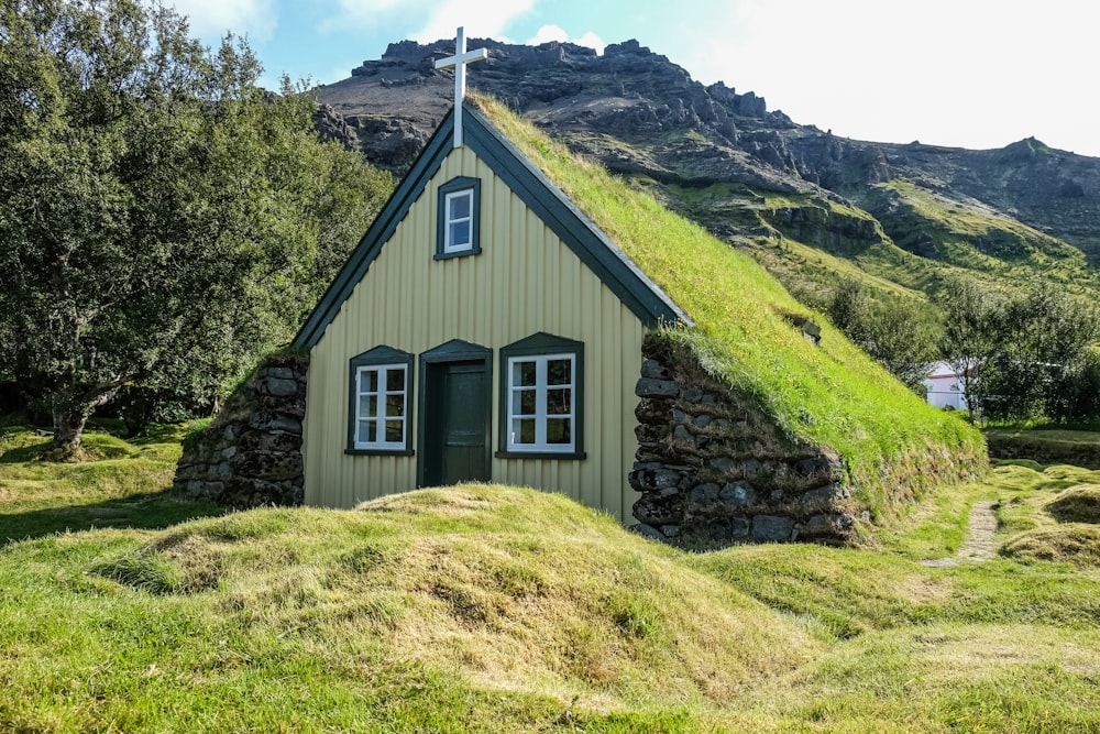 a small house with a grass roof on a hill