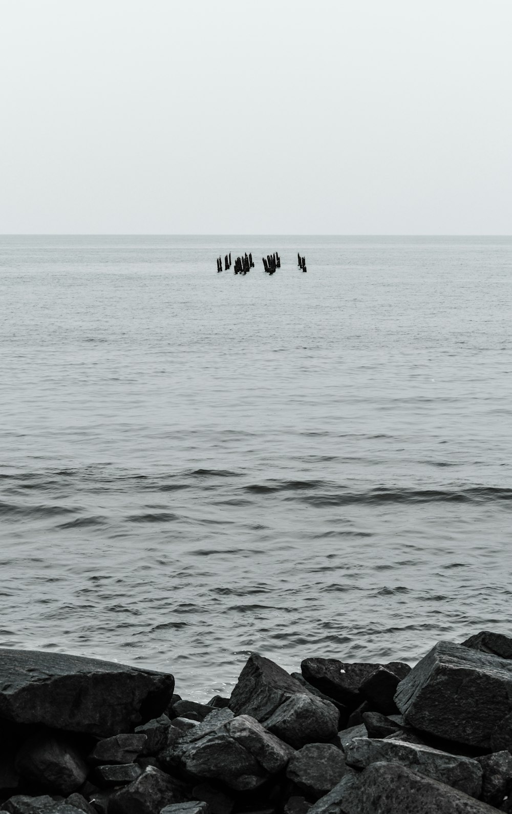 a black and white photo of the ocean and rocks