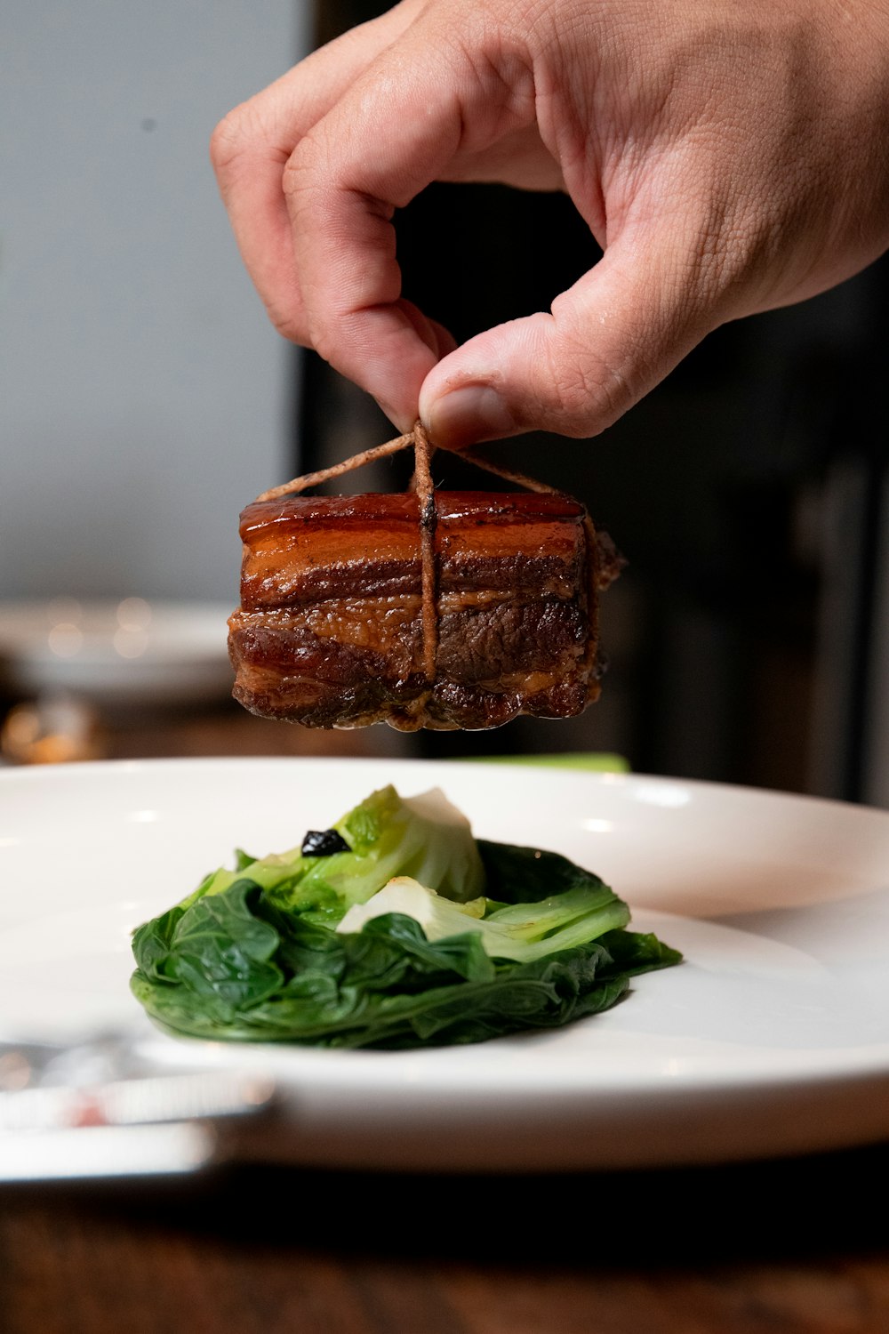 une personne tient un morceau de viande dans une assiette