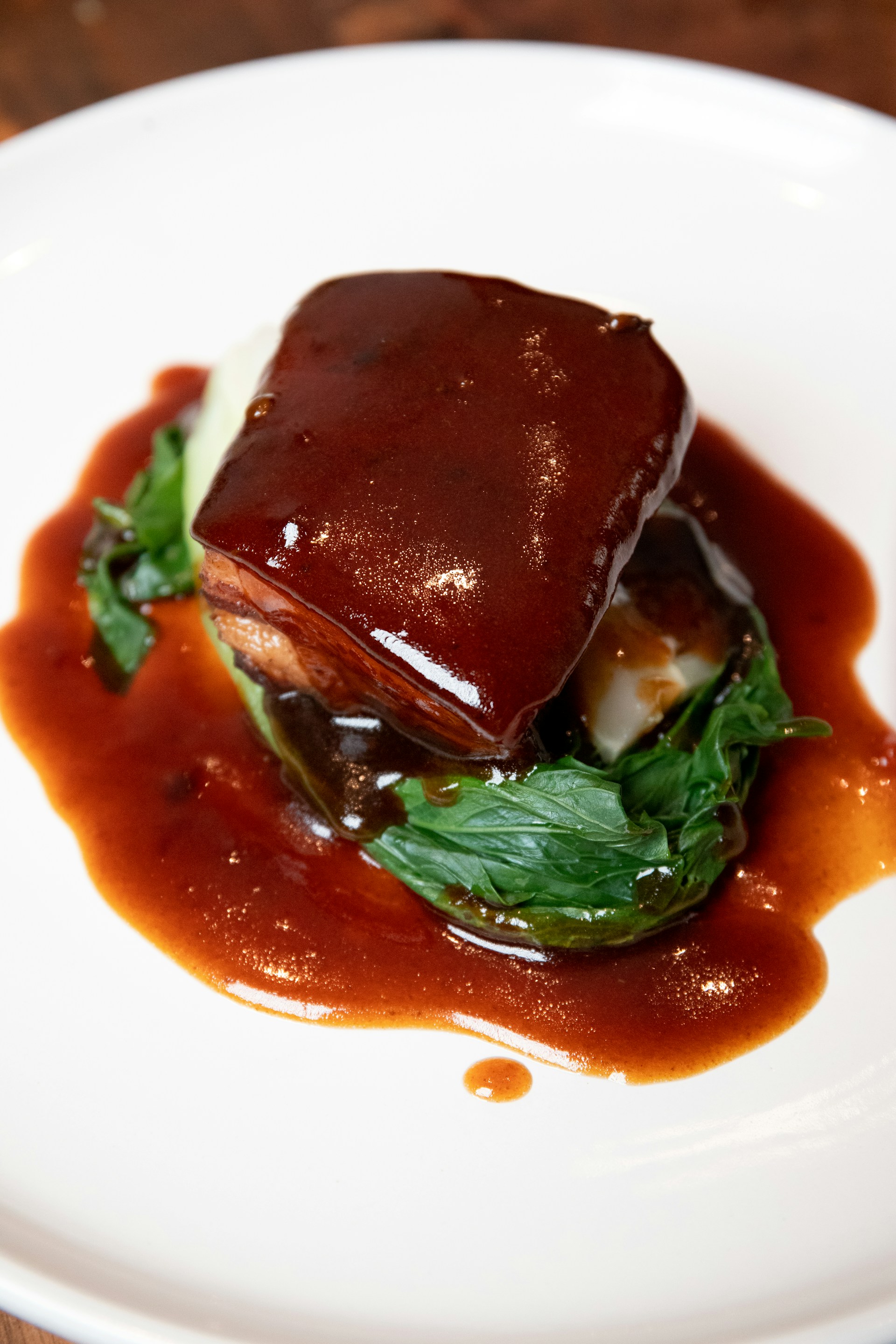 A beautifully plated dish of mole negro with rich, dark sauce contrasting against a cream-colored ceramic plate, set on a black linen tablecloth with subtle Aztec patterns.