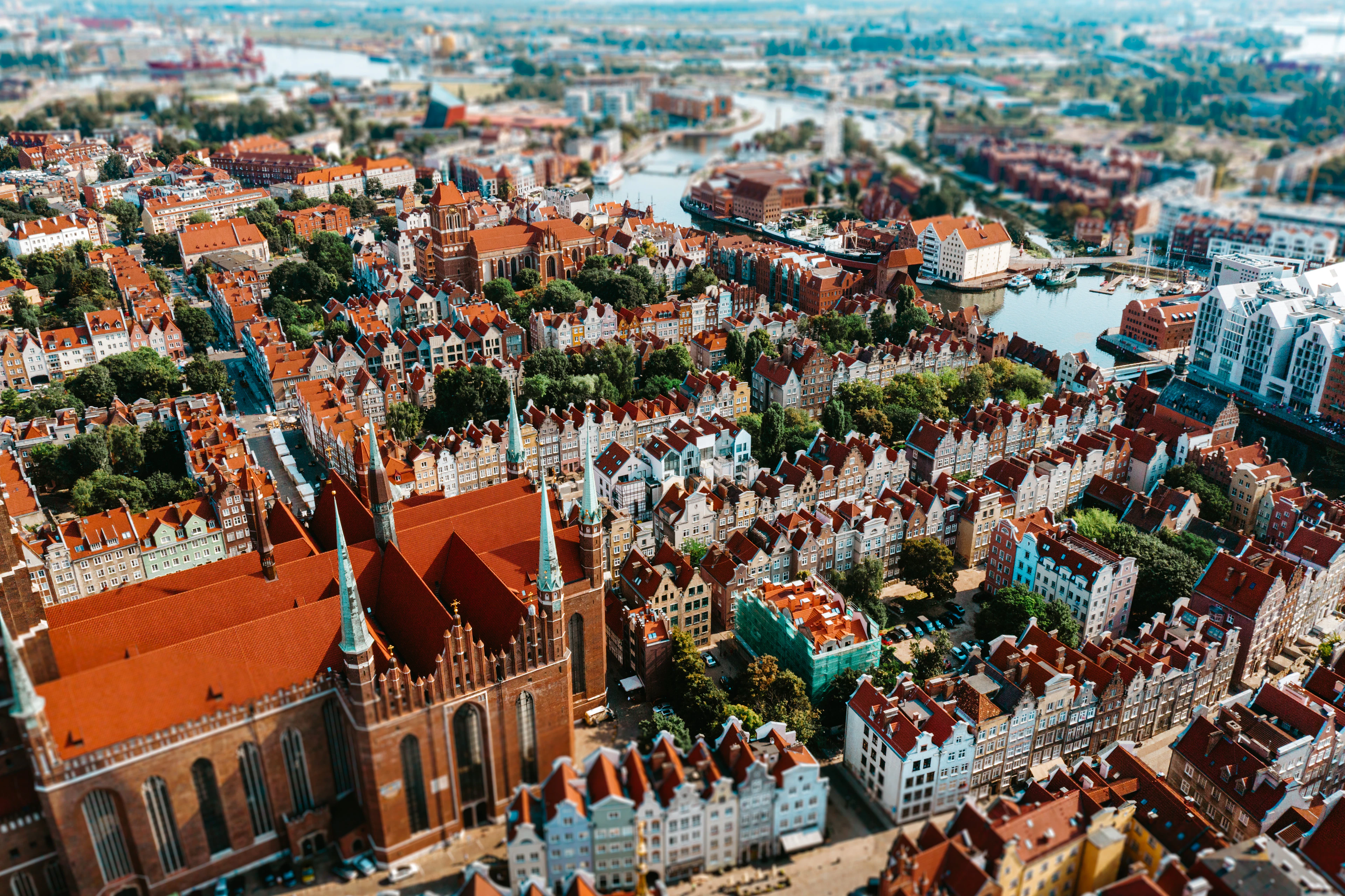 An aerial view of Gdańsk's Old Town red rooftops, with St. Mary's Church tower rising above the canal and gabled streets.