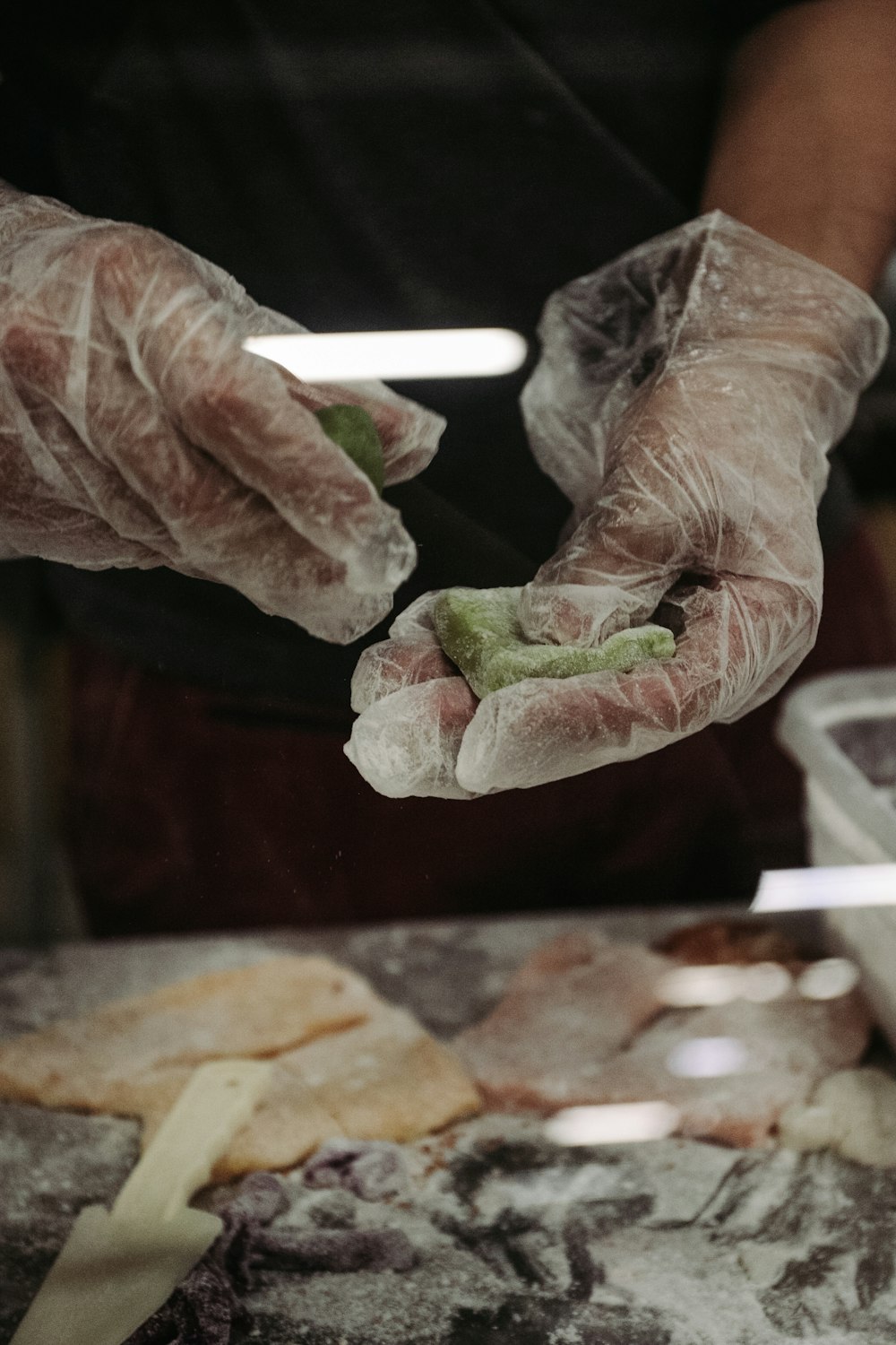 a person wearing gloves and holding a piece of food