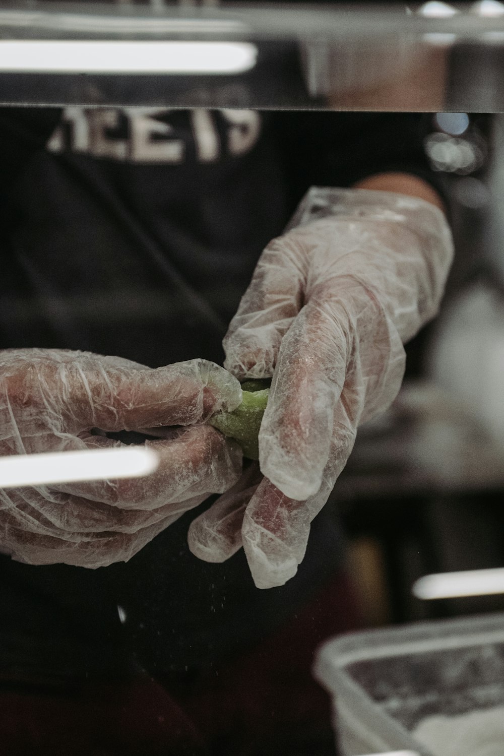 a person wearing gloves and holding a piece of food