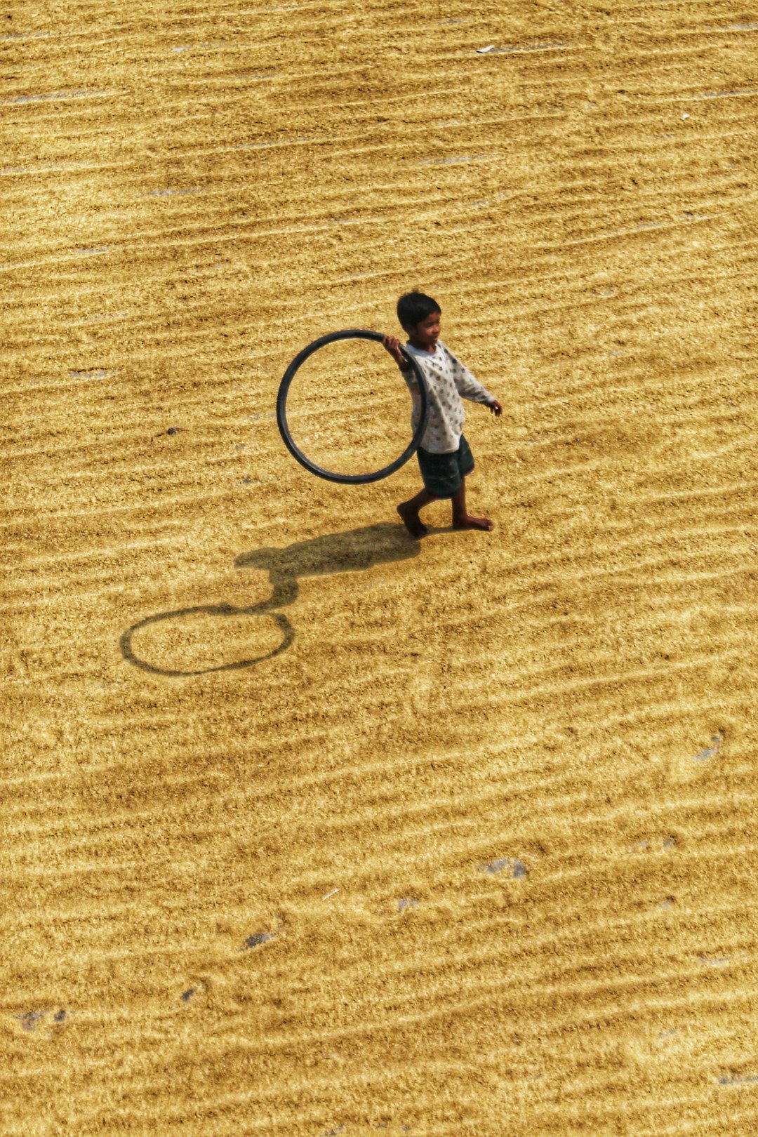 child in white shirt and blue denim jeans playing on brown field during daytime