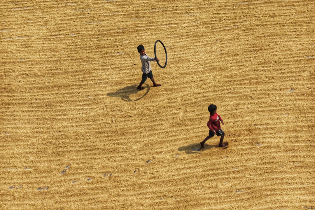 2 boys playing on brown sand during daytime