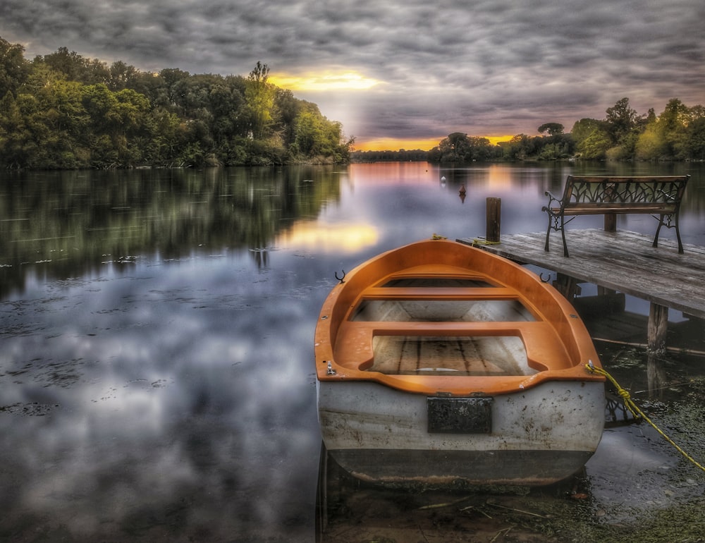 a boat sitting on top of a lake next to a dock