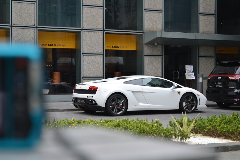 Un auto deportivo blanco estacionado frente a un edificio