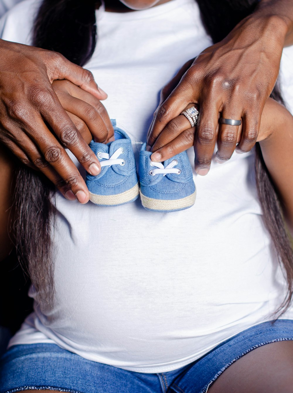 a pregnant woman holding a pair of blue shoes