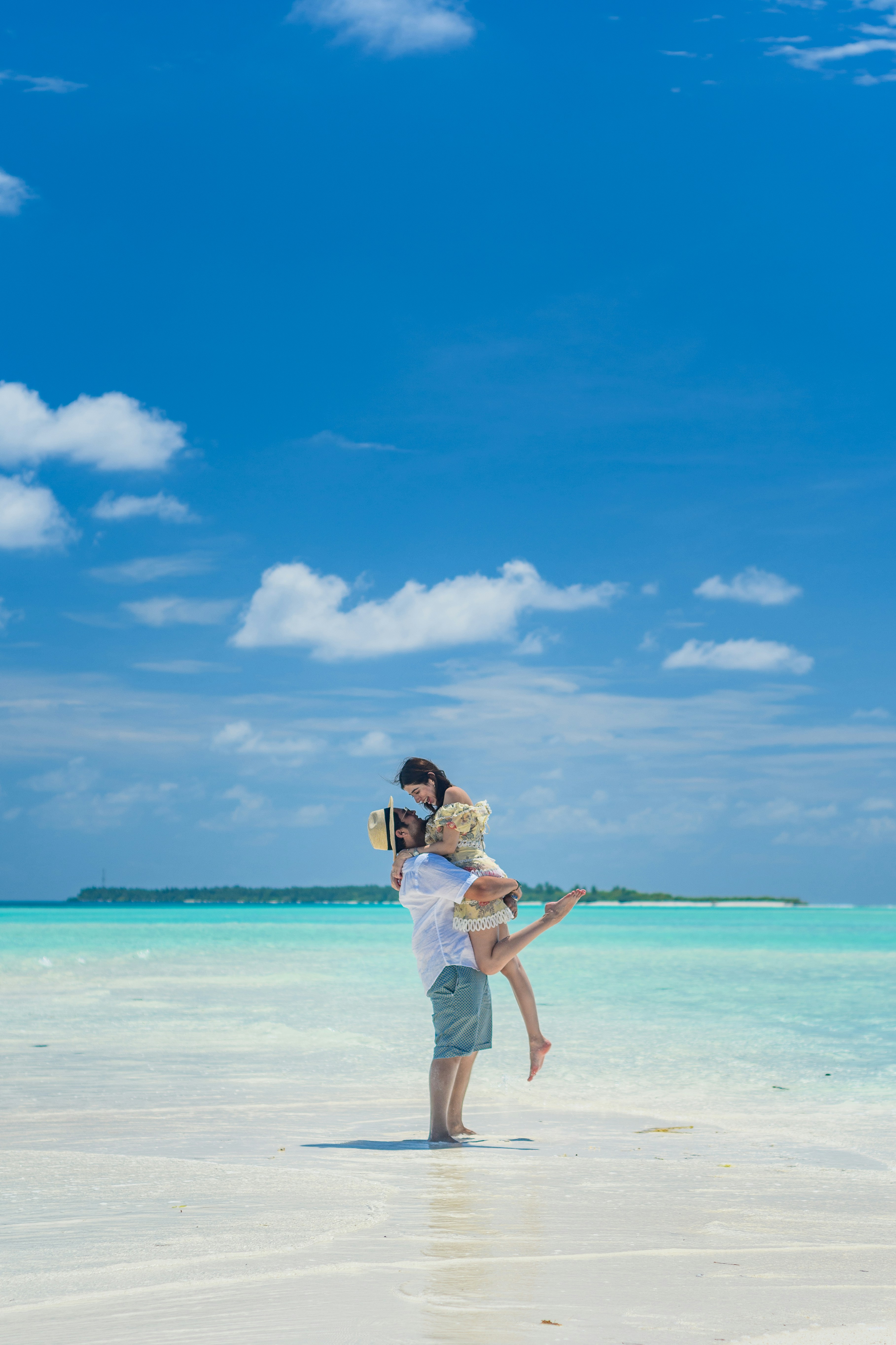 woman in white shirt and white shorts standing on beach during daytime