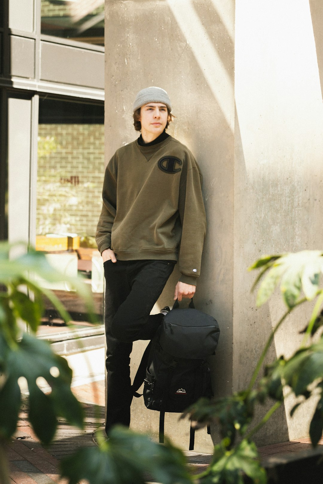 man in brown jacket and black pants sitting on concrete wall