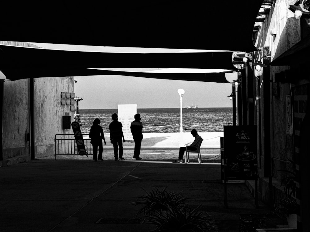 a group of people standing on a sidewalk next to the ocean