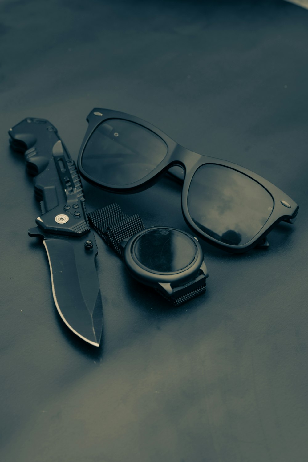 um par de óculos de sol, um pente e uma faca em uma mesa