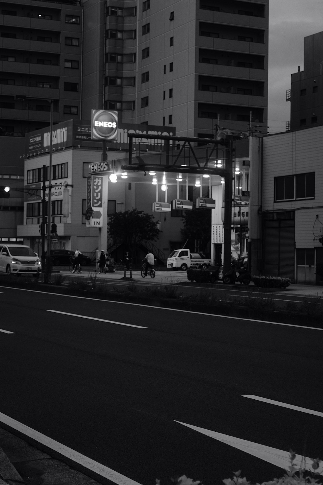 grayscale photo of street with cars parked beside building