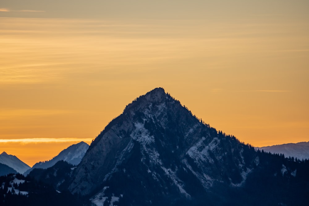 a mountain is silhouetted against a sunset sky