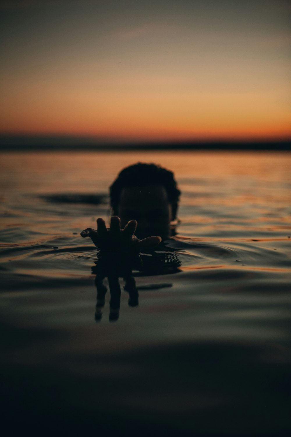 a person swimming in a body of water at sunset