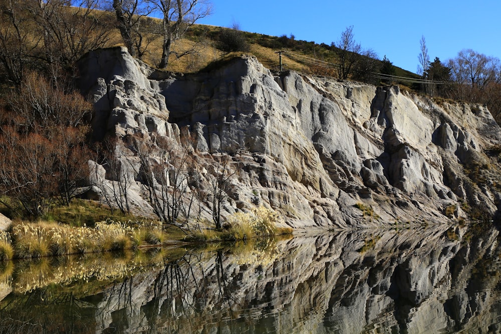 gray rocky mountain beside body of water during daytime