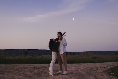Wide shot of a couple dancing under twinkling fairy lights at dusk.