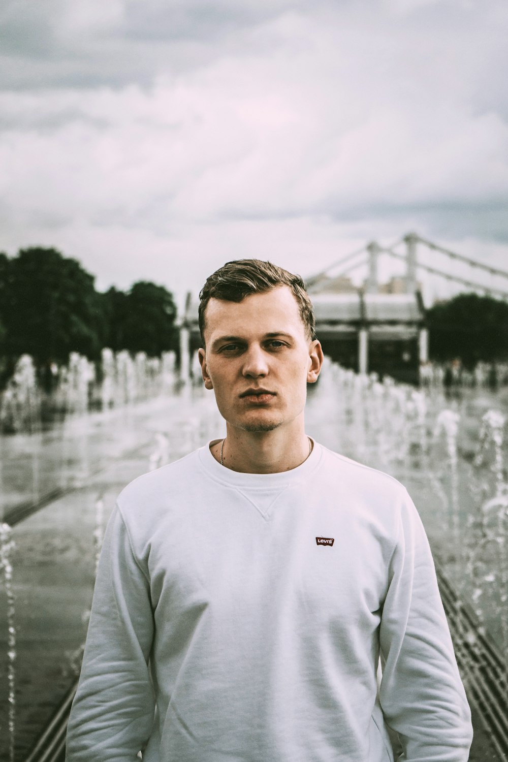 man in white crew neck shirt standing near body of water