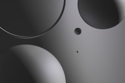 Various circular shapes in different sizes are positioned on a smooth, gradient background. The image primarily uses shades of gray, with a sleek and modern look.