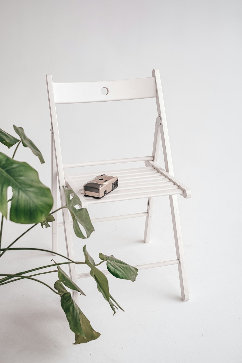 a white chair next to a plant and a book