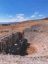 A rustic auditorium nestled in a dry, remote landscape under a vast blue sky.