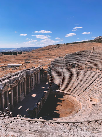 A rustic auditorium nestled in a dry, remote landscape under a vast blue sky.