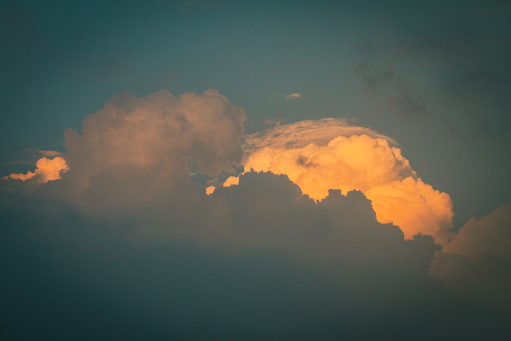 a plane flying through a cloudy sky at sunset