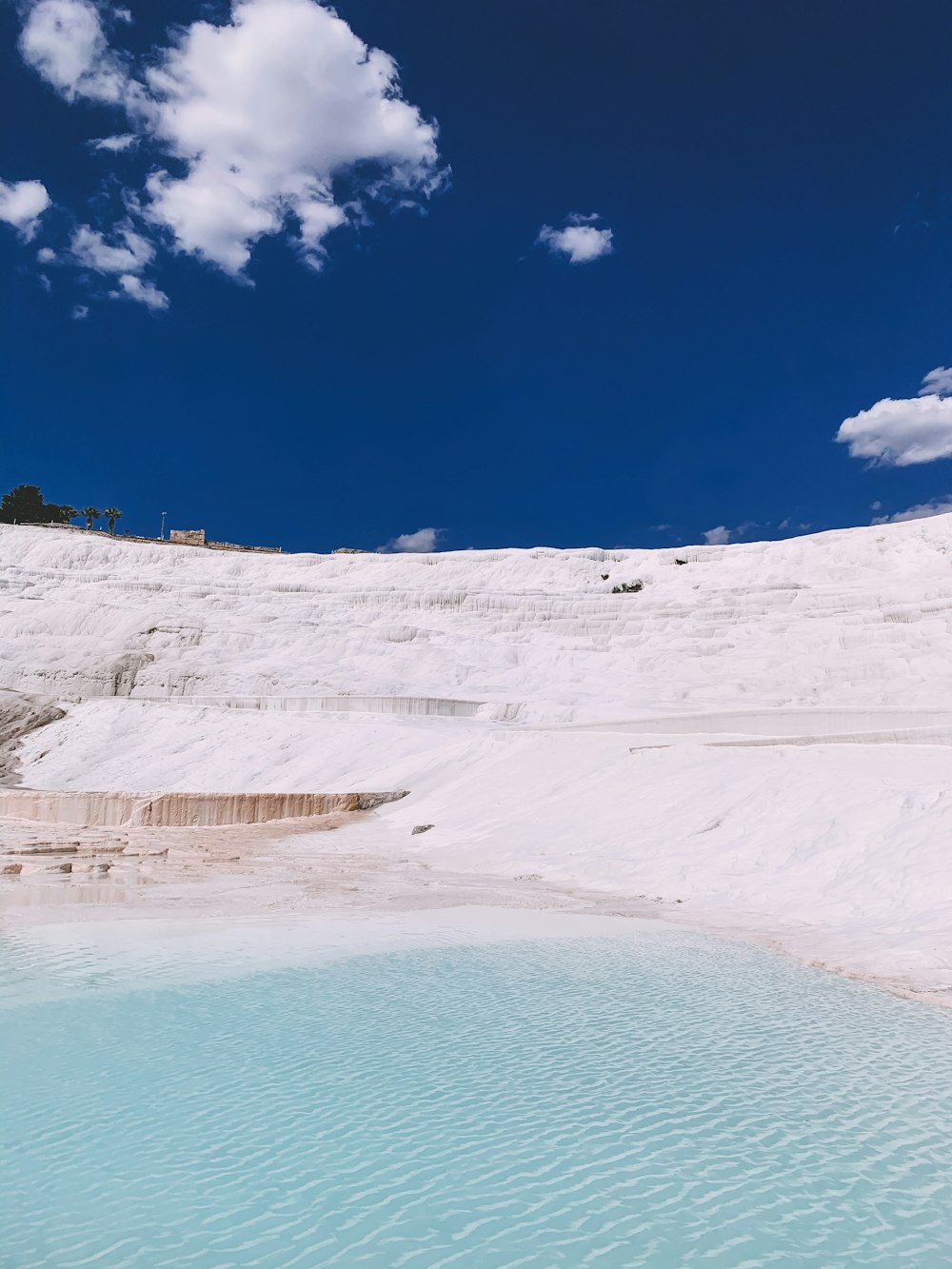 a pool of water in the middle of a snow covered hill