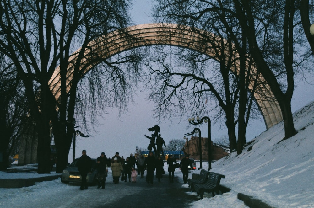 Menschen, die tagsüber auf schneebedecktem Boden unter der Brown Arch Bridge stehen
