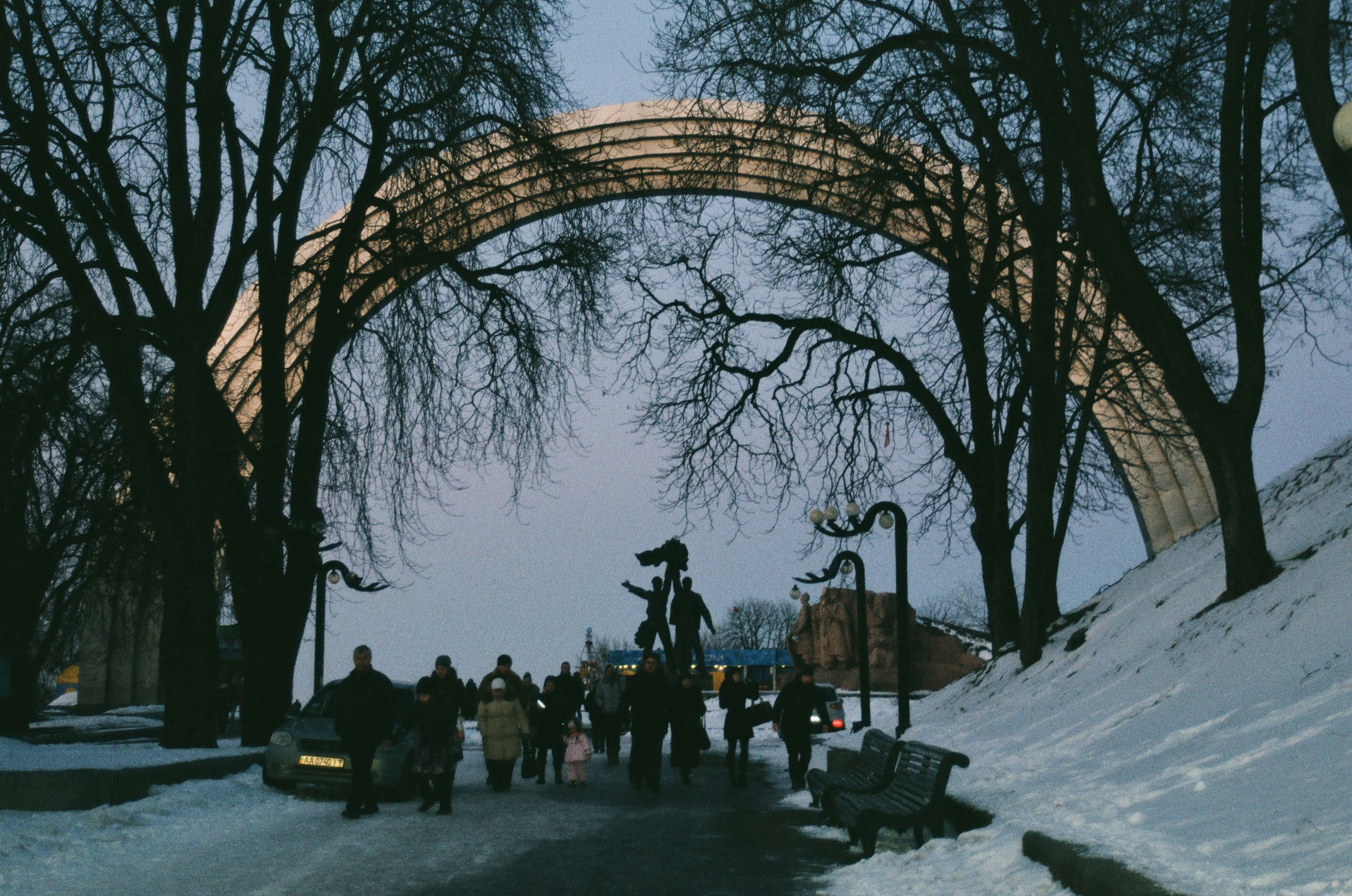 people standing on snow covered ground under brown arch bridge during daytime