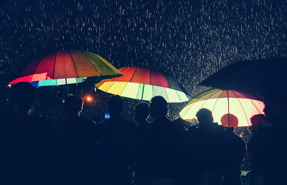 Eine Gruppe von Menschen, die unter Regenschirmen im Regen stehen