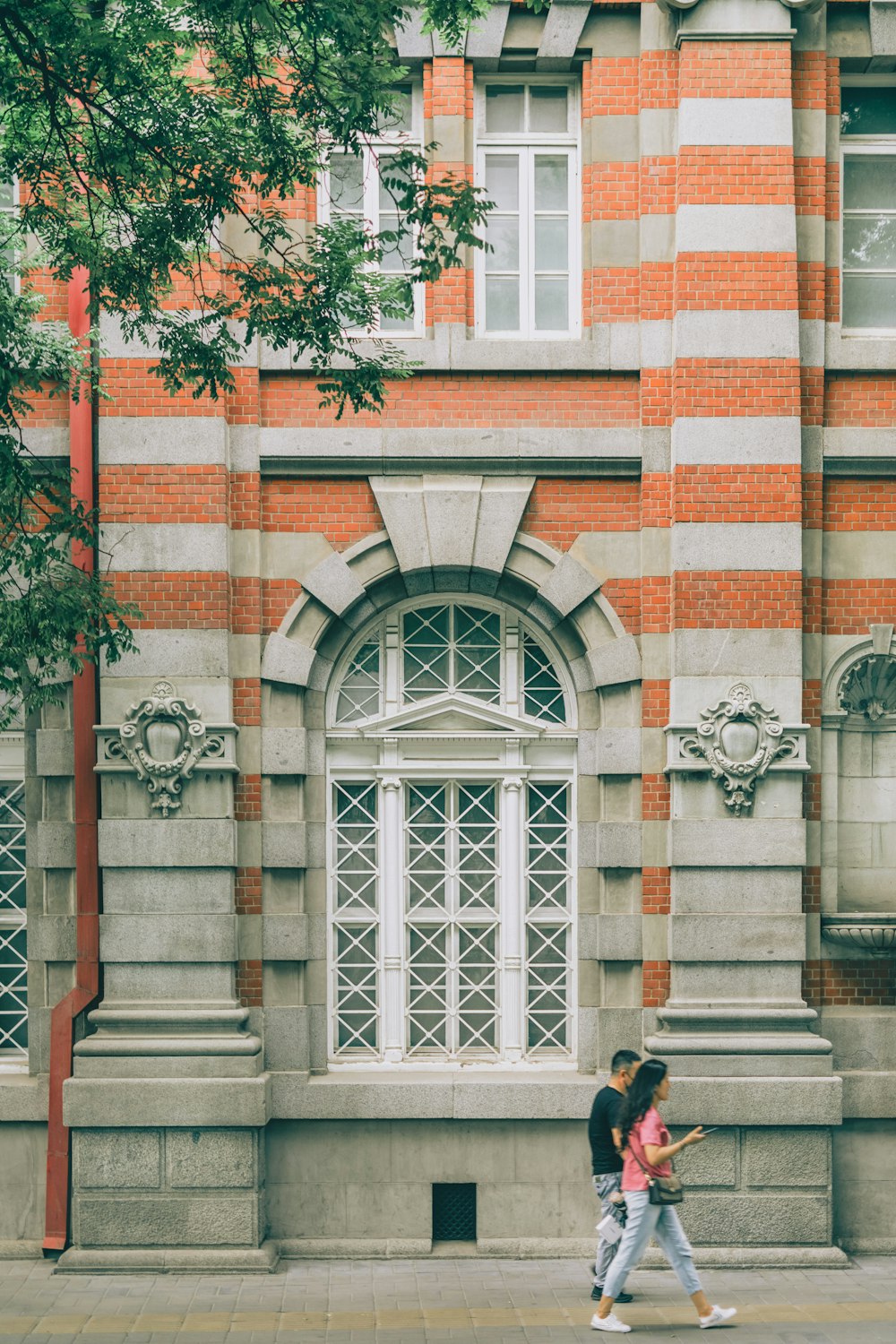 two people walking down a sidewalk in front of a building