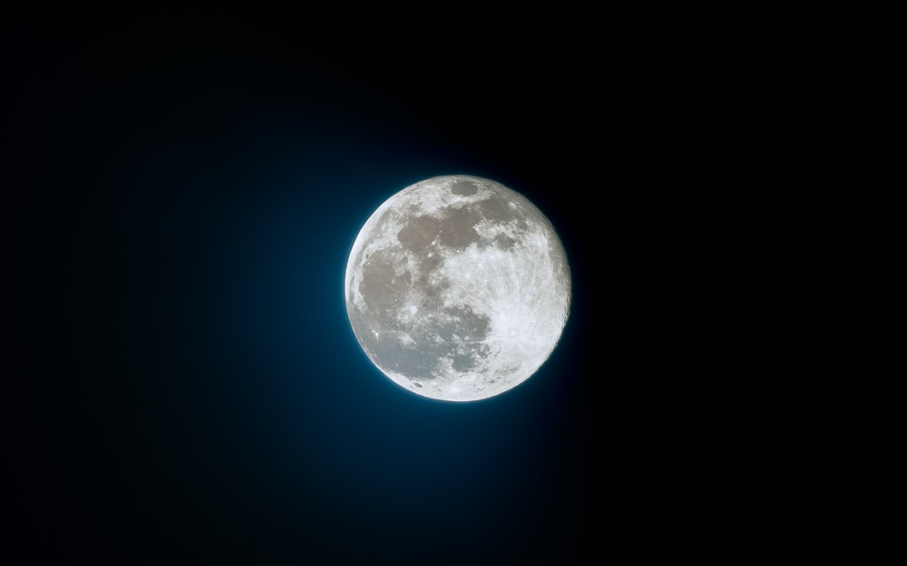 a full moon is seen in the dark sky