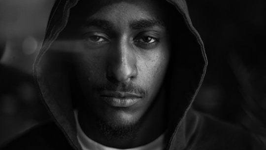 Close-up of a black hoodie with sharp white graphic print under moody lighting.