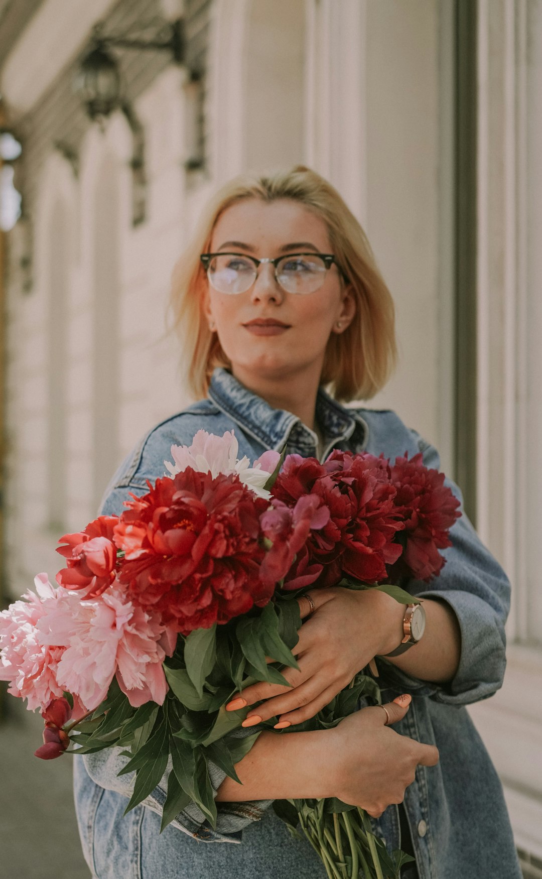 woman in blue denim jacket holding pink flower bouquet