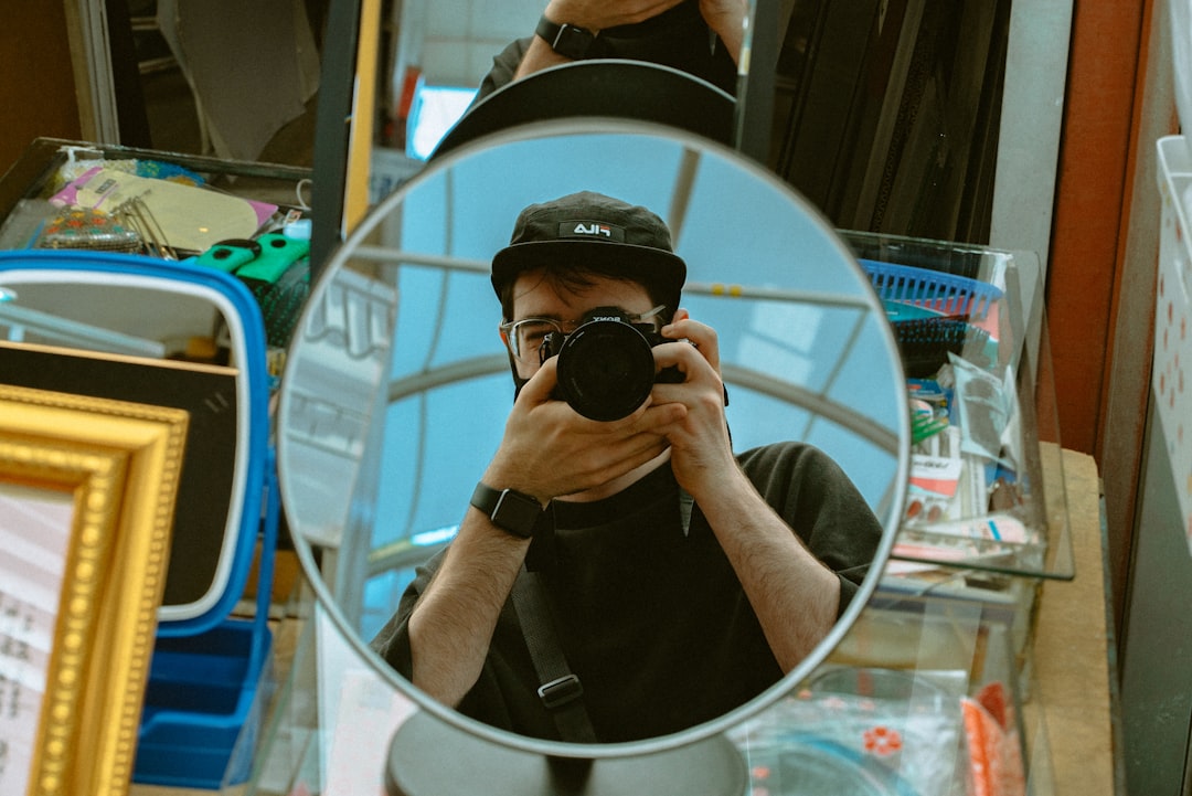 man in black t-shirt holding black dslr camera