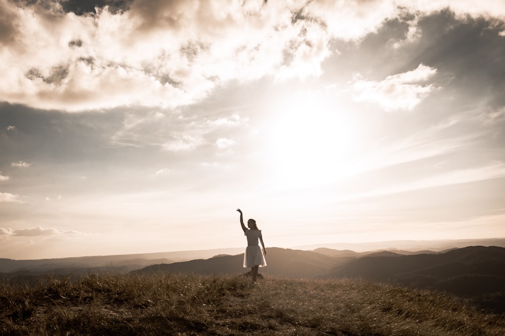 Une femme debout au sommet d’une colline couverte d’herbe