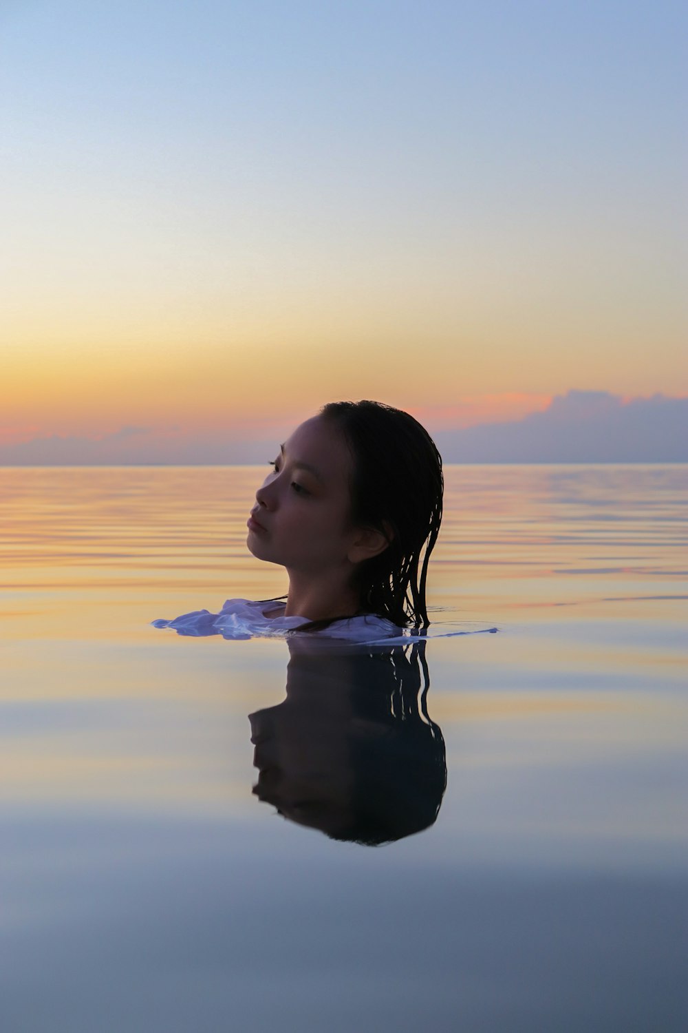 a woman is floating in the water at sunset