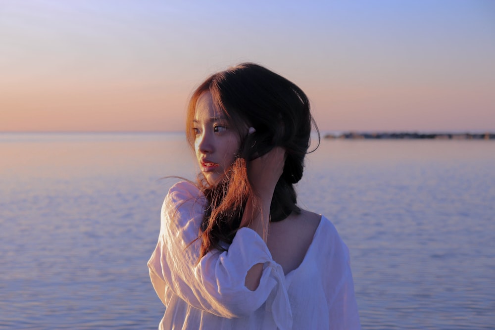 woman in white long sleeve shirt standing near body of water during daytime