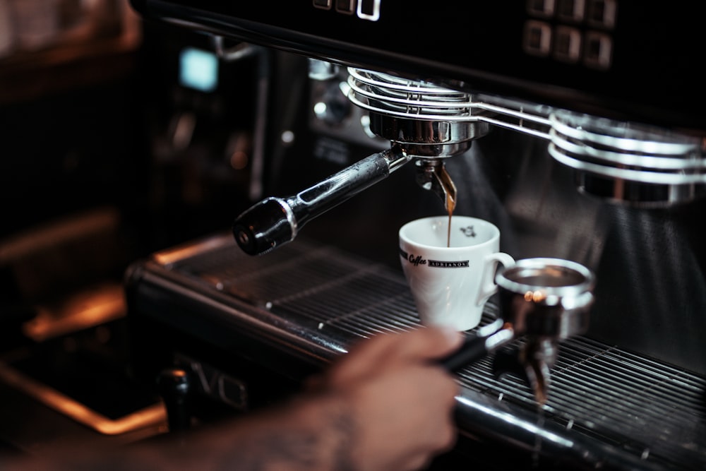 a person is filling a cup of coffee