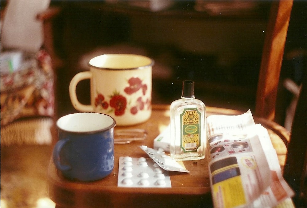 a wooden table topped with a cup and a bottle of alcohol
