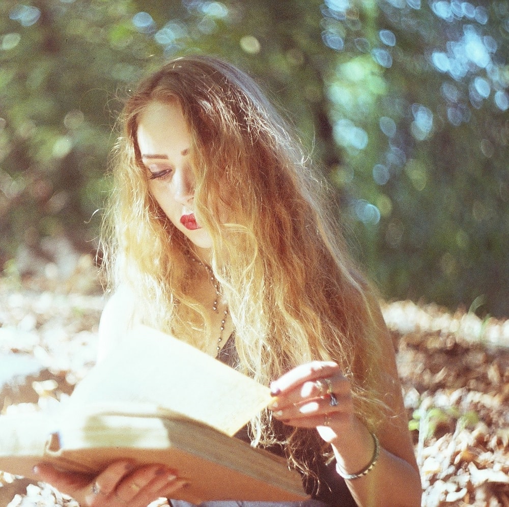 a woman sitting on the ground reading a book