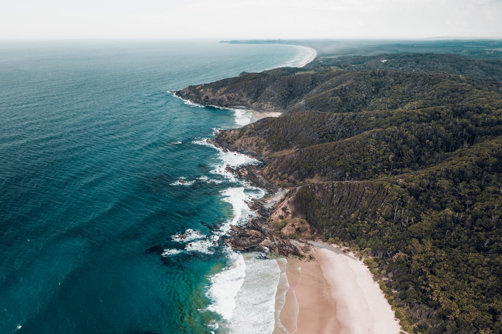 aerial view of green and brown mountain beside body of water during daytime