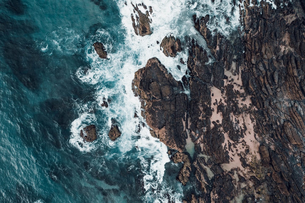 brown and white rock formation beside body of water