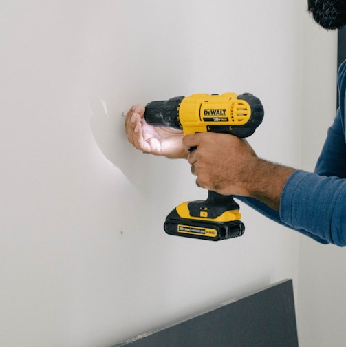 a man is holding a drill and a cordless drill