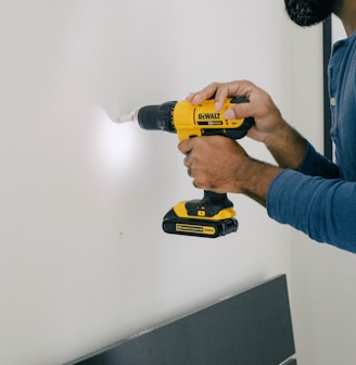 person holding yellow and black cordless hand drill