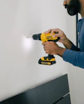 person holding yellow and black cordless hand drill