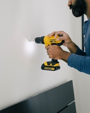 person holding yellow and black cordless hand drill