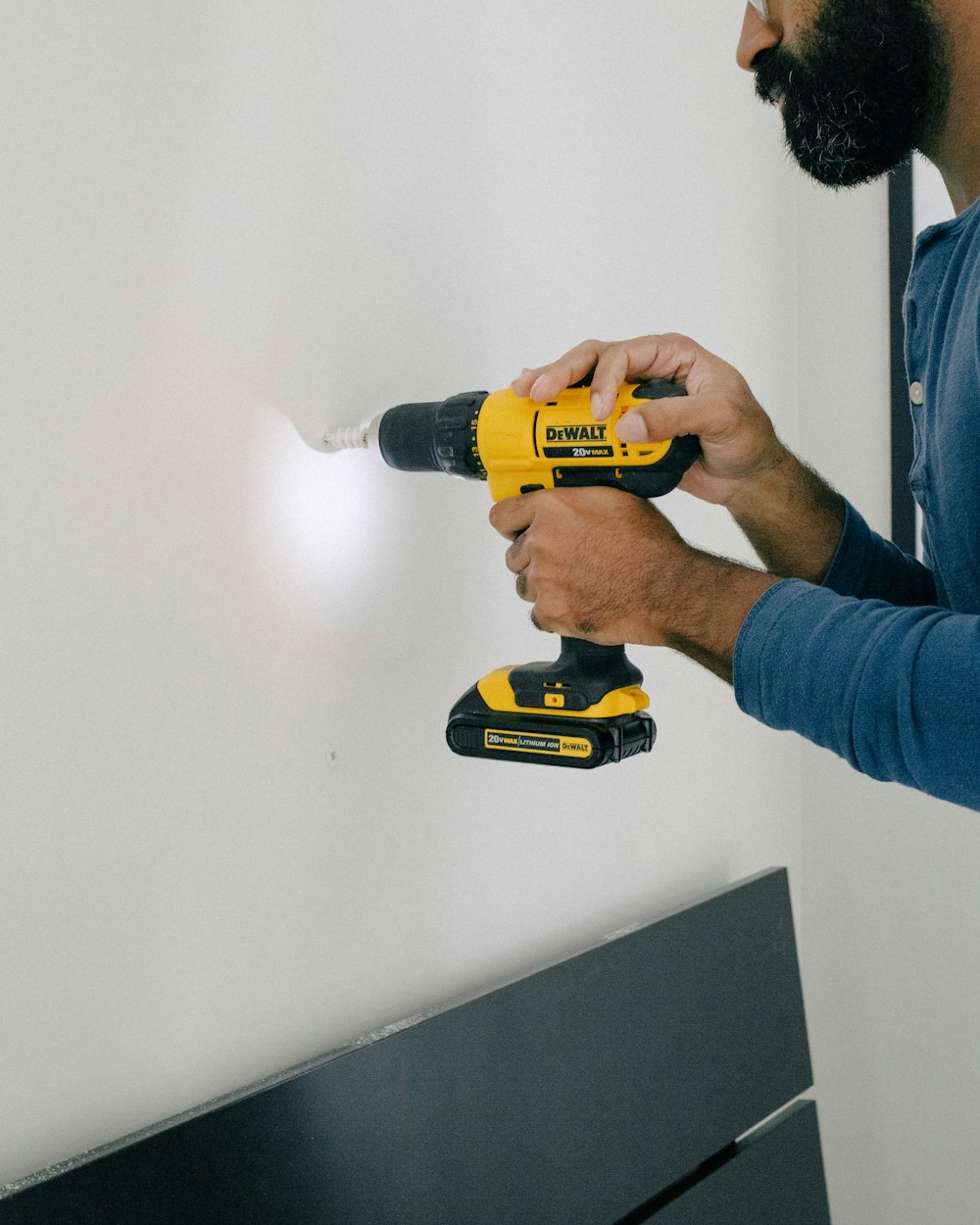 Persona che tiene il trapano a mano a batteria giallo e nero